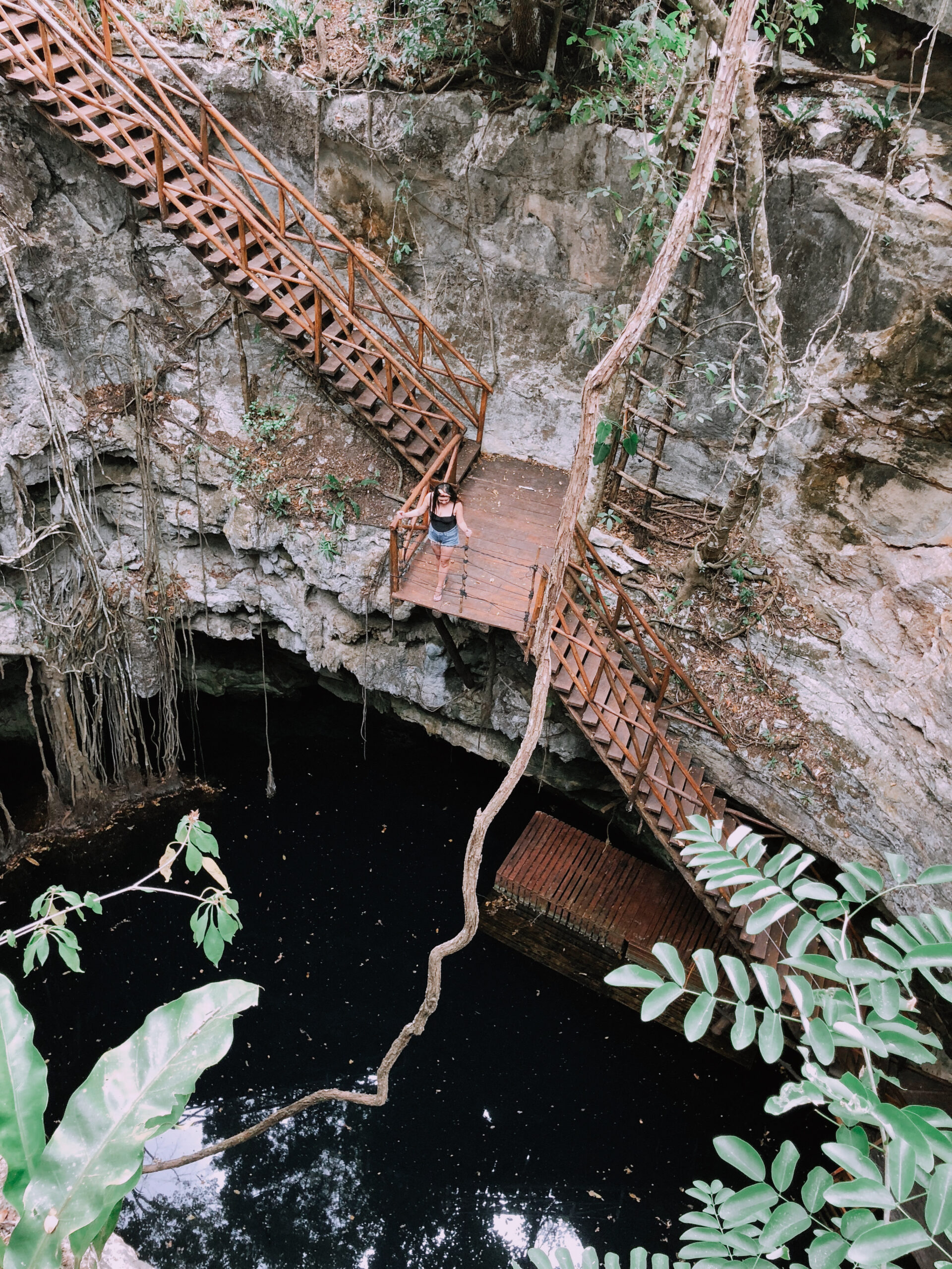 Woman on wooden stairs leading into a cenote in Merida, Mexico.