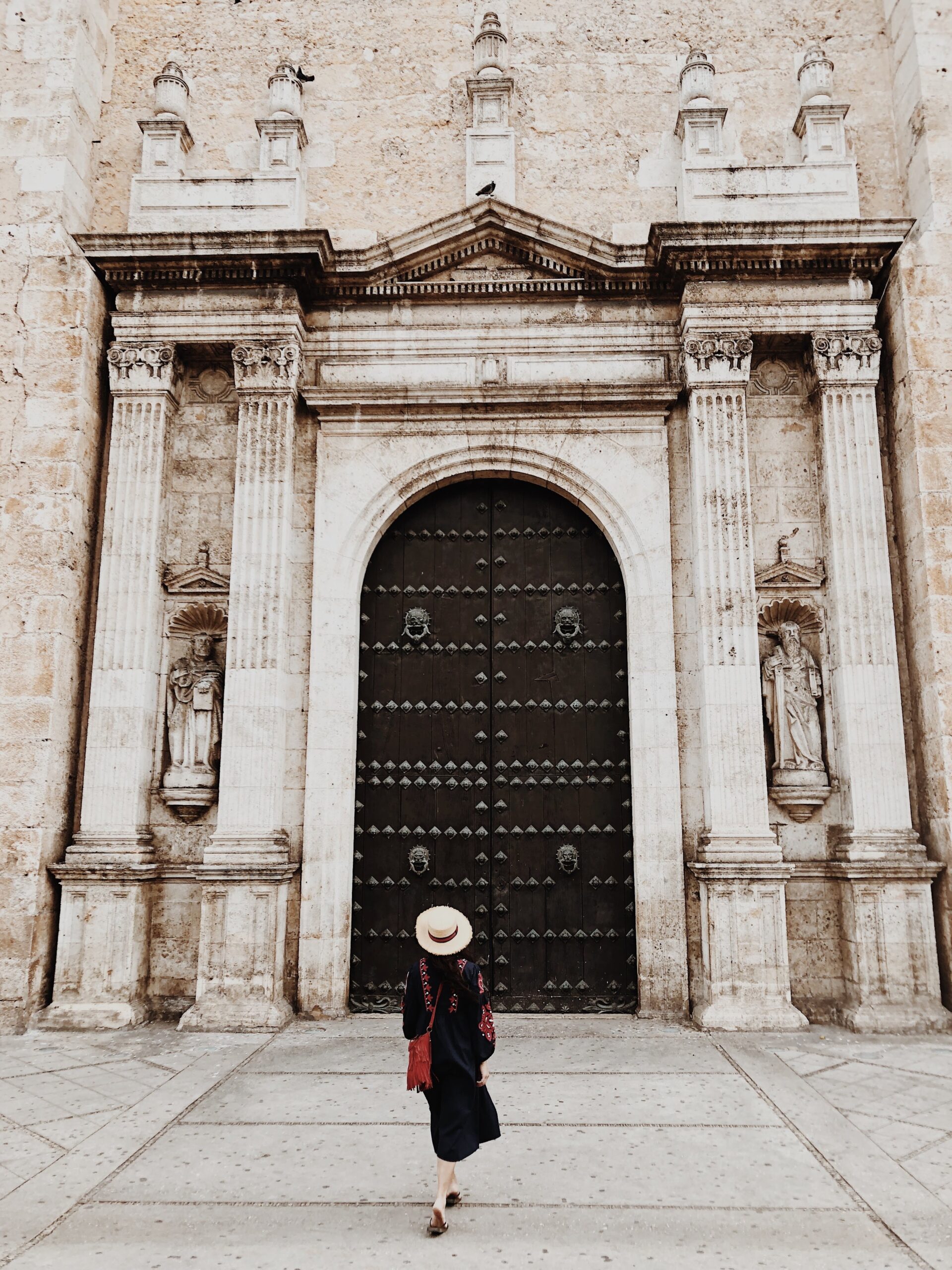 Woman in straw hat at grand cathedral entrance in Merida, Mexico