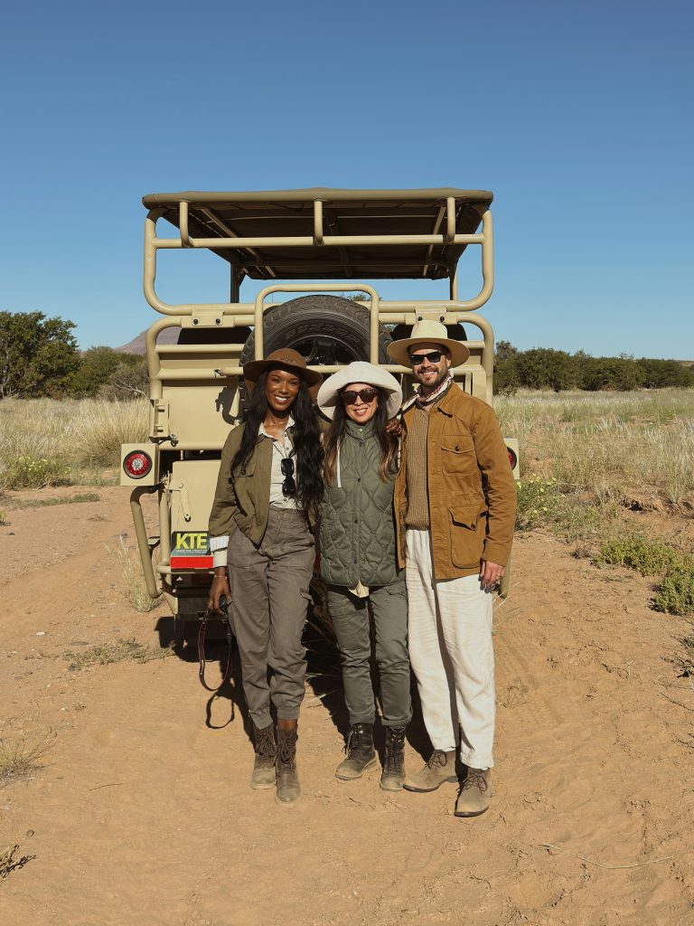 Three people in safari hats pose in front of a safari jeep, travel and lifestyle blog