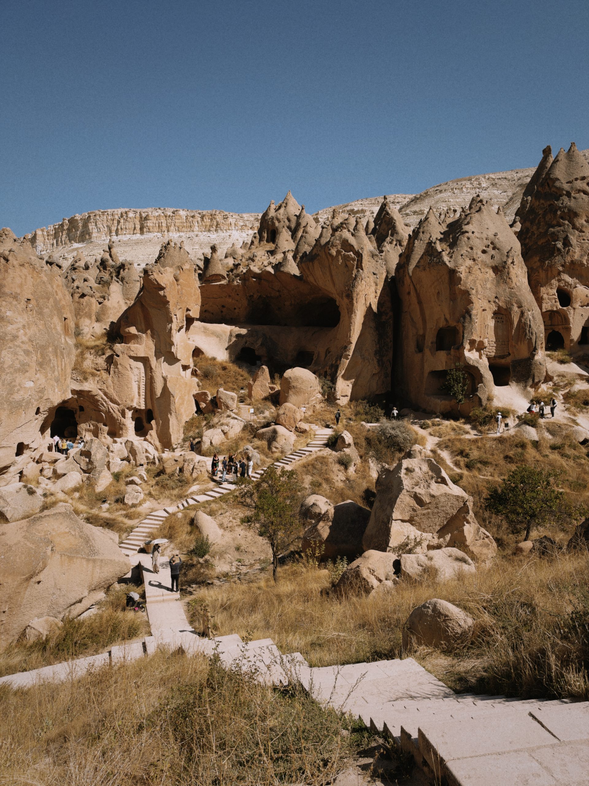 Cave dwellings, rock formations and visitors in Cappadocia