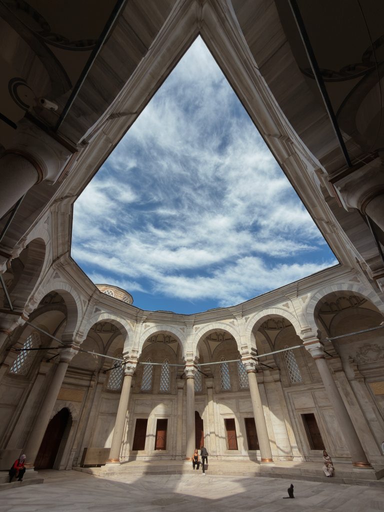 Ottoman mosque courtyard with arches, columns, and a triangular sky view