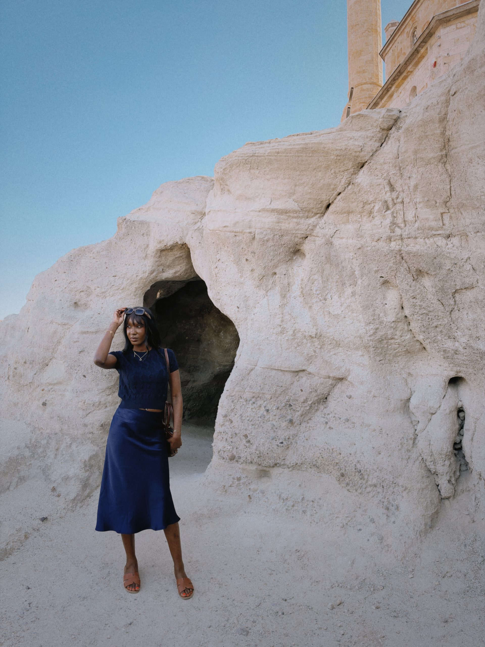 Woman in a blue skirt standing at a cave entrance in Cappadocia