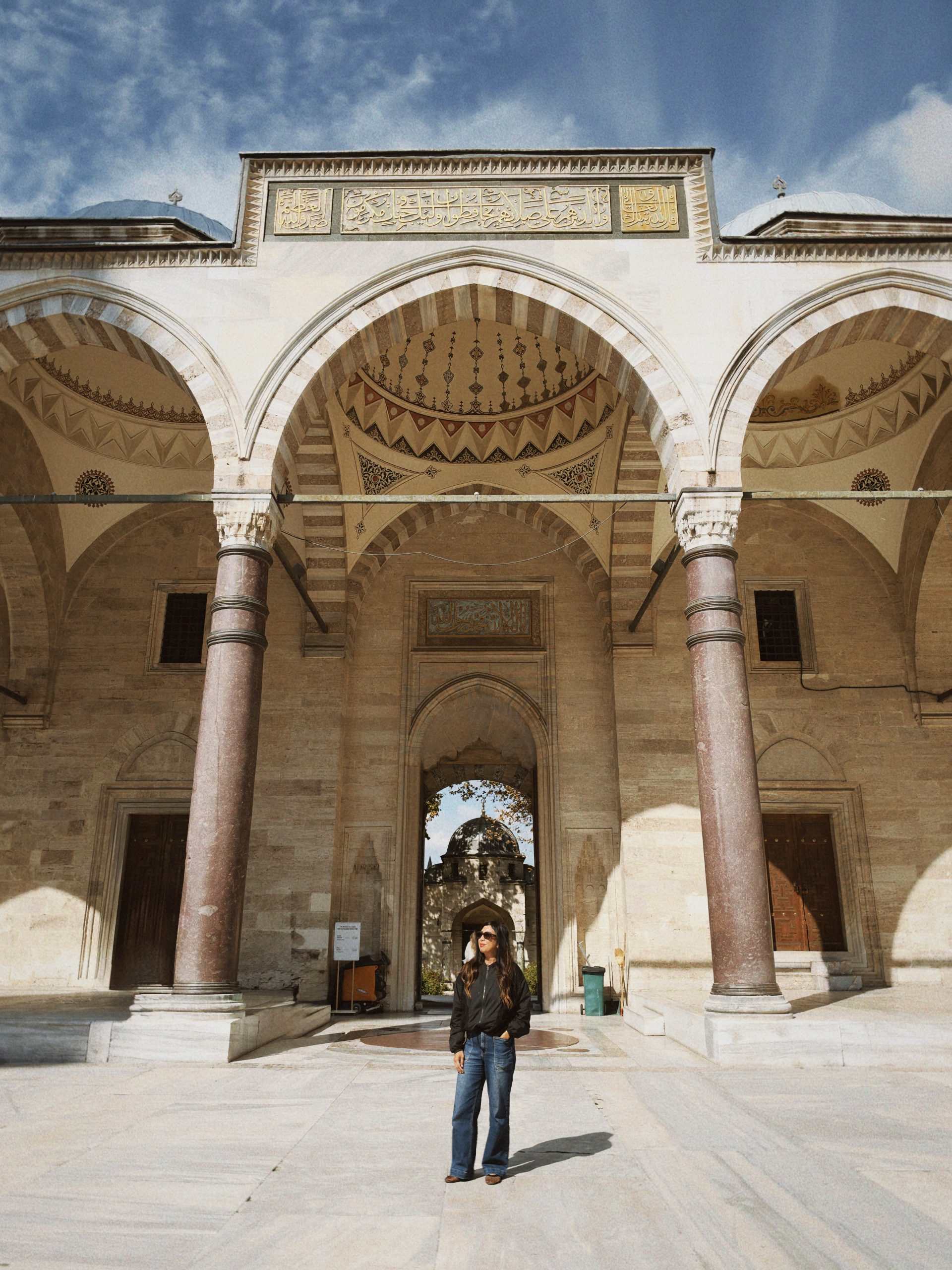 Woman standing beneath the arches of an Ottoman mosque courtyard in Istanbul